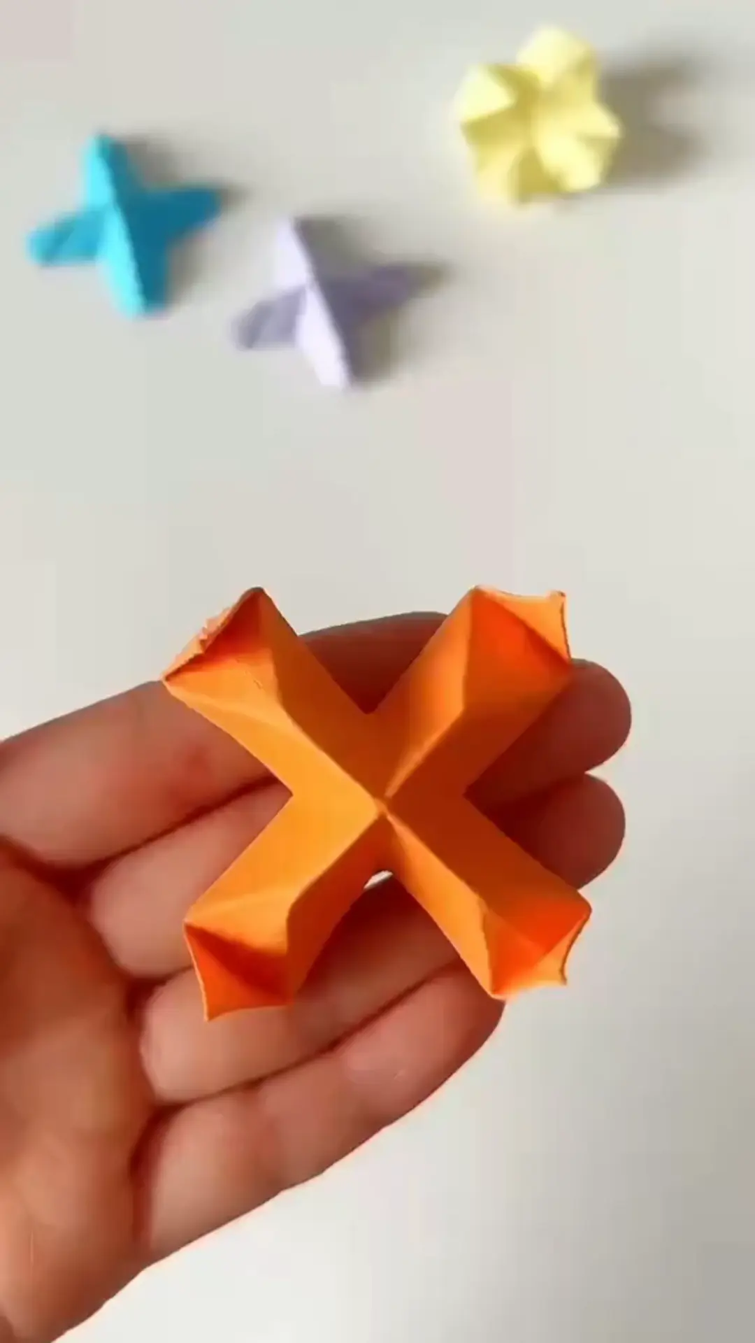 Completed orange origami star displayed on clean white surface