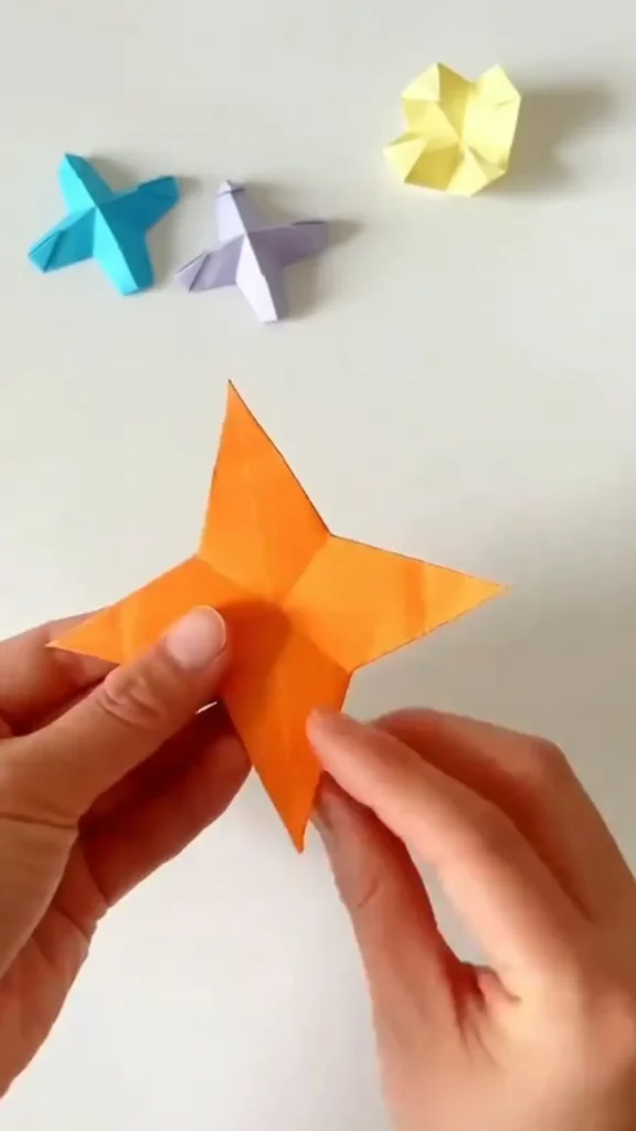 Completed orange origami star displayed on clean white surface